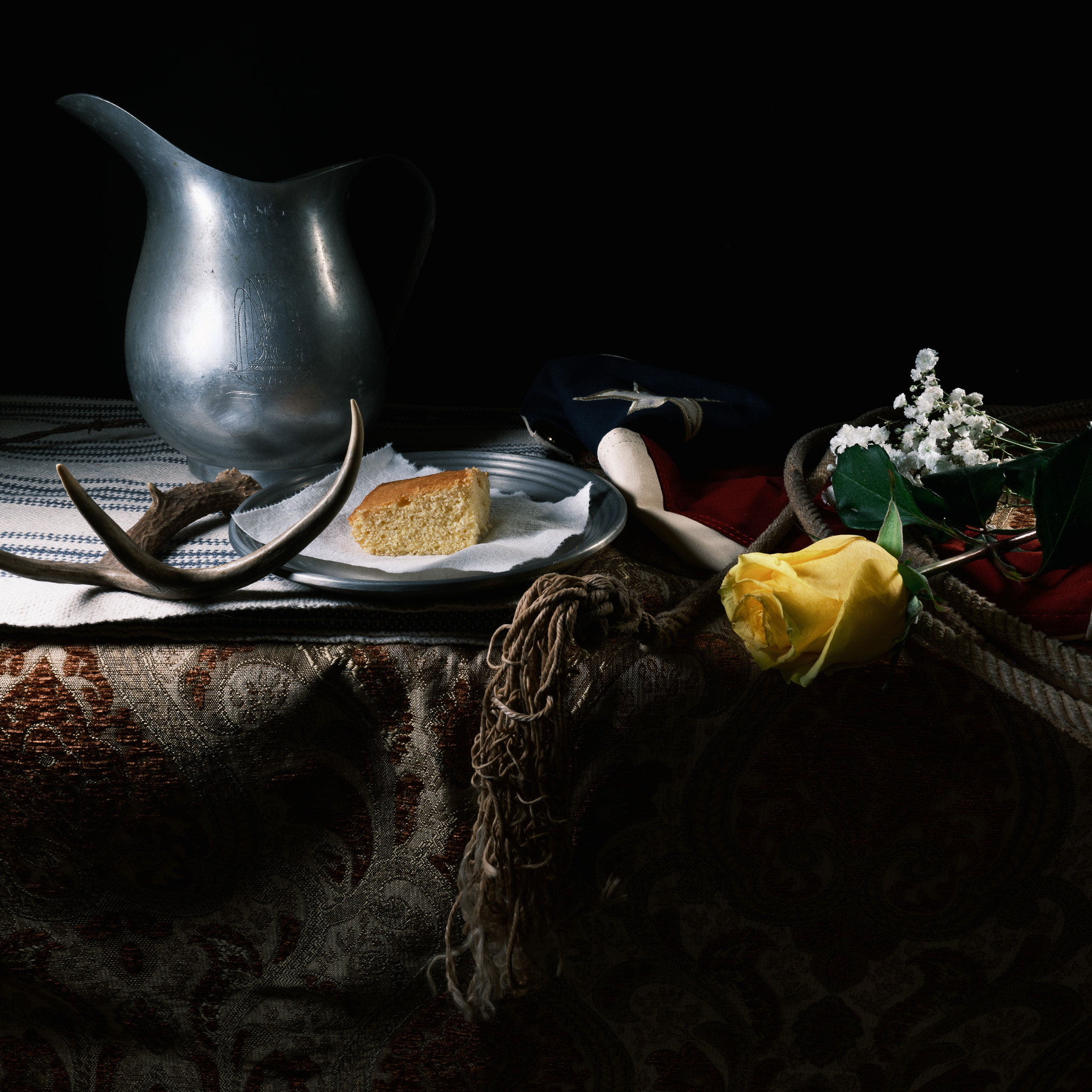 Still-life photography of cornbread, texas flag, and a yellow rose
